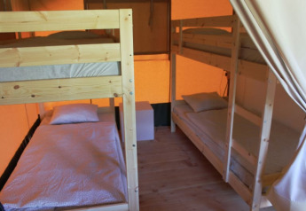 Inde i en safari-telt på Camping Prima i Tjekkiet med køjesenge og en hyggelig atmosfære.
