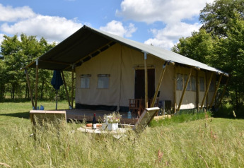 Safari tent at Camping Domaine Bleu Celeste in France, set in grassy outdoors with trees and blue sky.