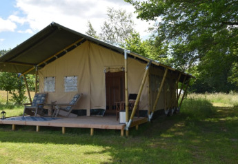 Safari tent at Camping Domaine Bleu Celeste in France, featuring a wooden deck and outdoor chairs.