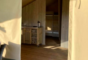 Ingang van een safaritent op Camping de Peelweide in Nederland met houten vloer en kitchenette binnenin.