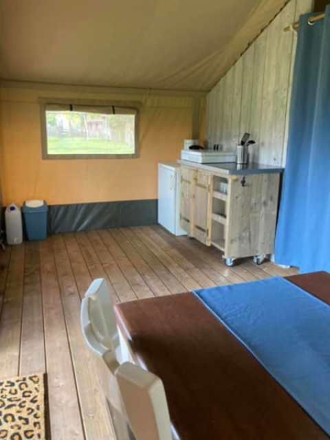 Vista interior de una tienda safari en Camping de Peelweide, Países Bajos, con cocina y mesa de comedor.