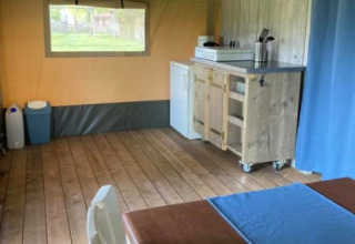 Vista interior de una tienda safari en Camping de Peelweide, Países Bajos, con cocina y mesa de comedor.