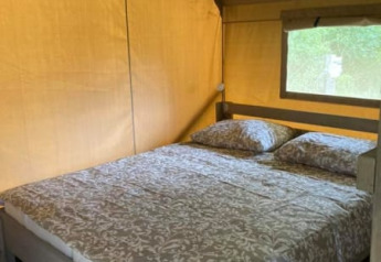 Indvendig billede af en safari telt med en dobbeltseng på Camping de Peelweide i Holland, set i dagslys.