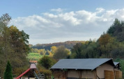 Safari tent with private sanitary at Camping Drei Spatzen, Germany, set in a green field with trees around.