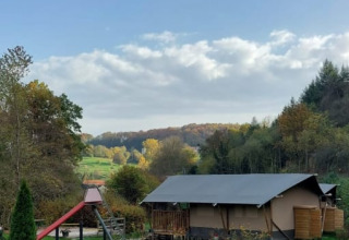 Safaritent met privé sanitair op Camping Drei Spatzen in Duitsland, met uitzicht op groene velden en bomen.