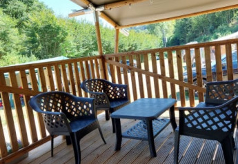 Terraza cubierta con muebles de plástico en la tienda Safari + sanitario de Camping Drei Spatzen, Alemania.