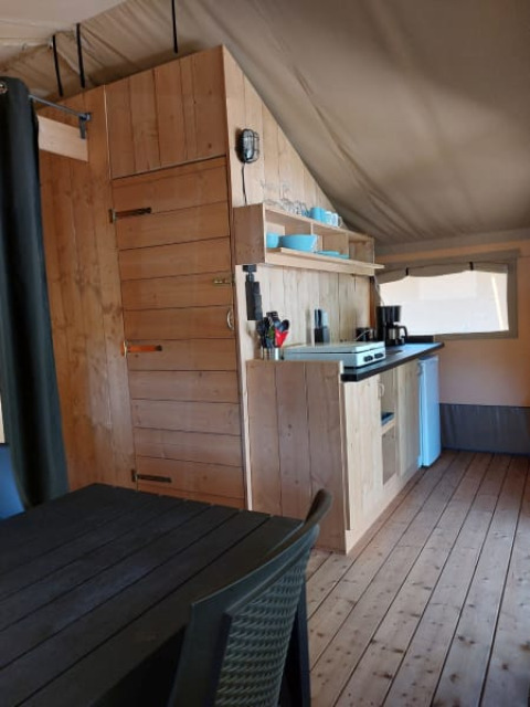 Interior view of Safari tent + sanitary at Camping Drei Spatzen in Germany, featuring kitchen and dining area.