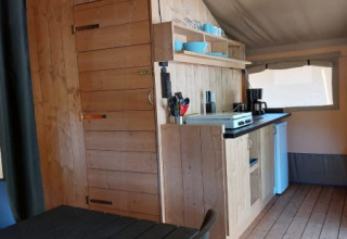 Interior view of Safari tent + sanitary at Camping Drei Spatzen in Germany, featuring kitchen and dining area.