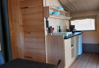 Vista interna della Safari tent + sanitary al Camping Drei Spatzen in Germania, con cucina e tavolo da pranzo.