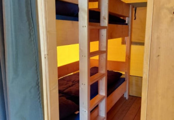 Interno di una tenda safari con letti a castello in legno al Camping Drei Spatzen in Germania.