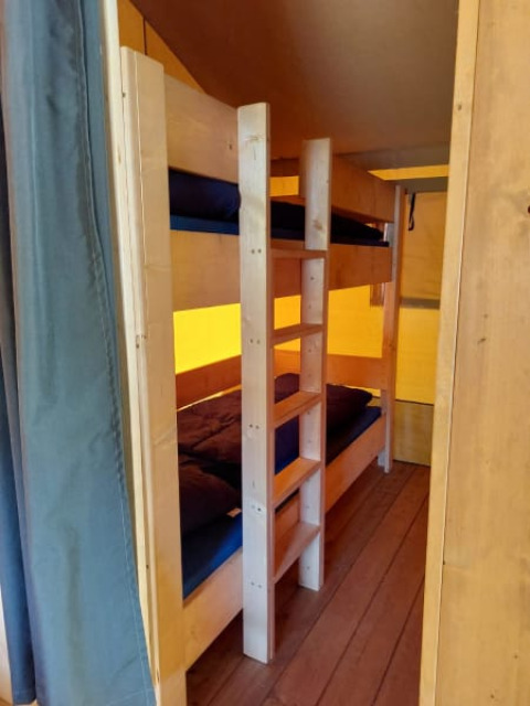 Inde i en safaritelts hytte med køjesenge og træinteriør på Camping Drei Spatzen i Tyskland.