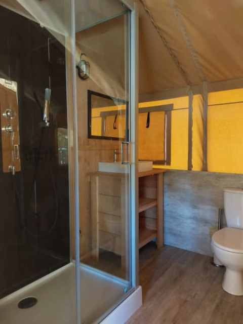 Bathroom inside a safari tent at Camping Drei Spatzen in Germany, featuring a shower, toilet, and sink.