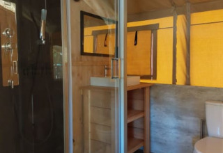 Bathroom inside a safari tent at Camping Drei Spatzen in Germany, featuring a shower, toilet, and sink.