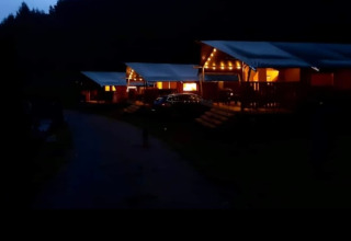 Photo du soir d'une tente safari avec sanitaires au Camping Drei Spatzen en Allemagne, éclairée chaleureusement.