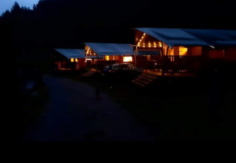 Evening photo of a safari tent with sanitary facilities at Camping Drei Spatzen in Germany, warmly lit up.
