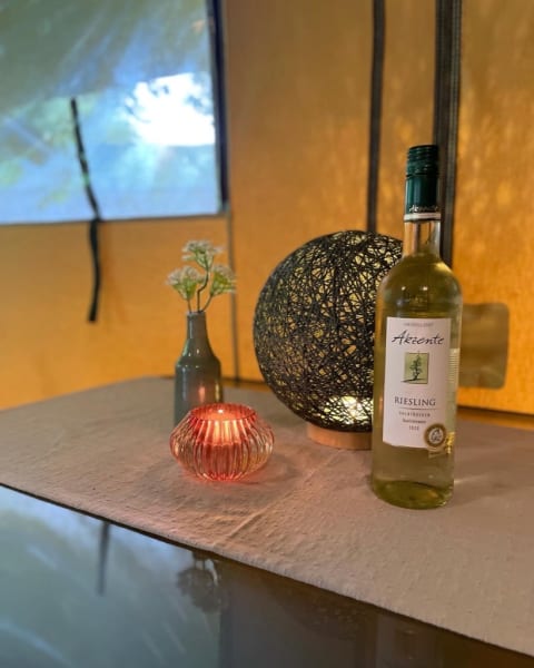 Safari-Zelt bei Camping Drei Spatzen in Deutschland, dekoriert mit Wein, Kerze und stilvollen Accessoires.