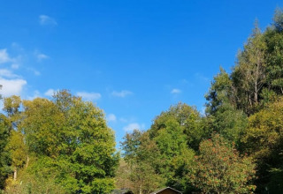 Safarizelt auf Camping Drei Spatzen in Deutschland, umgeben von grünen Bäumen und blauem Himmel.