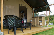Safarizelt auf Camping La Dolce Vita in den Niederlanden mit Holzterrasse, Sitzgruppe und Outdoor-Küche.