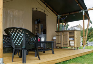 Tenda safari al Camping La Dolce Vita nei Paesi Bassi con terrazza in legno, sedie e cucina esterna.