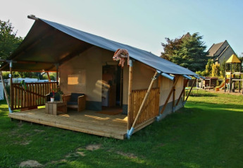 Tienda safari con terraza de madera y baño en Camping La Dolce Vita, Países Bajos, parque infantil visible.