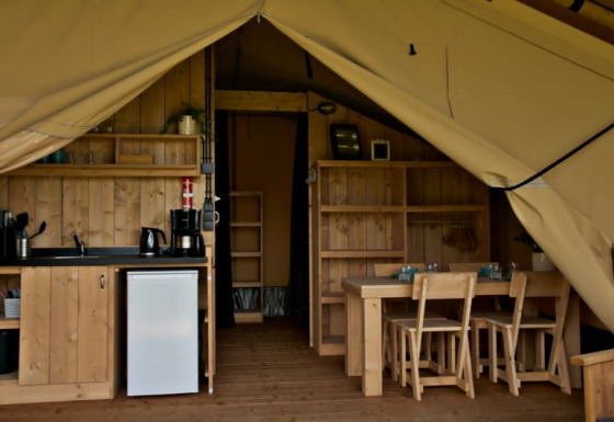 Interior de tienda safari con instalaciones sanitarias en Camping La Dolce Vita, Países Bajos, muebles de madera.