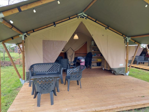 Safari tent at Camping Yttermalungs in Sweden featuring wooden decking, plastic chairs, and indoor lighting.