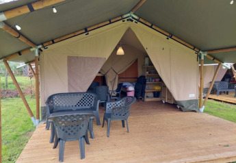 Safaritent bij Camping Yttermalungs in Zweden met houten terras, plastieken stoelen en lamp binnen.