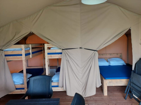 Binnenkant van safaritent bij Camping Yttermalungs in Zweden met stapelbedden, tweepersoonsbed en stoelen.