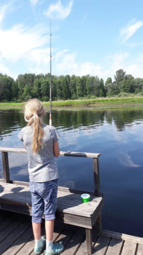 Bambina che pesca da un molo di legno presso il lago vicino a Safari tent al Camping Yttermalungs, Svezia.