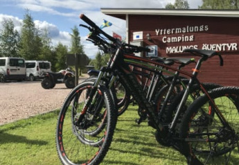 Several mountain bikes are parked on grass near the safari tent at Camping Yttermalungs, Sweden, sunny day.