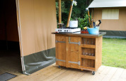 Cucina da esterno su ruote accanto a una tenda safari a Camping de Meibeek, Paesi Bassi, con fornello a gas e utensili.