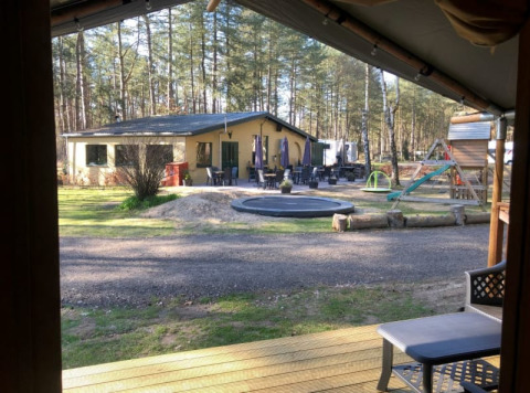 Vista da una tenda safari con servizi igienici privati al Camping Siësta in Belgio, parco giochi visibile.