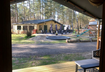Vista da una tenda safari con servizi igienici privati al Camping Siësta in Belgio, parco giochi visibile.
