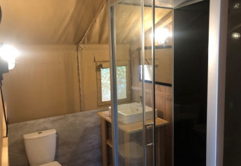 Modern bathroom in a safari tent at Camping Siësta in Belgium, featuring a shower, toilet, and sink.