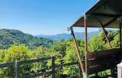 View from a safari tent terrace overlooking green hills and blue sky, perfect for a relaxing getaway.