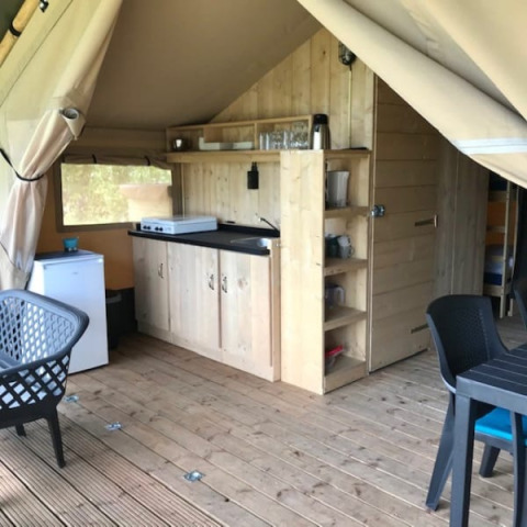 Innenaufnahme eines Safarizelts mit Küchenbereich und Holzmöbeln auf Camping de Zwammenberg, Niederlande.