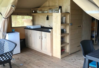 Innenaufnahme eines Safarizelts mit Küchenbereich und Holzmöbeln auf Camping de Zwammenberg, Niederlande.