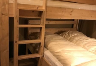 Interior de una litera de madera con ropa de cama en una tienda safari en Camping de Zwammenberg, Países Bajos.