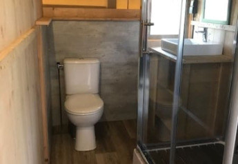 Bathroom inside a safari tent at Camping de Zwammenberg with toilet, shower cabin and washbasin.