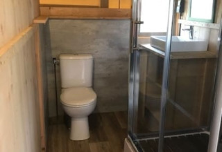 Bathroom inside a safari tent at Camping de Zwammenberg with toilet, shower cabin and washbasin.