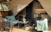 Safari tent with cozy seating area and table on a wooden deck at Recreation Park Keiheuvel, Belgium.