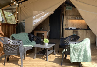 Tienda safari con mesa y sillas en una terraza de madera en el Parque Recreativo Keiheuvel, Bélgica.