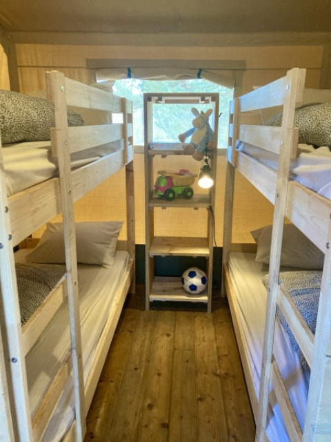 Interior of a safari tent at Recreation Park Keiheuvel, Belgium, with bunk beds and children's toys on shelves.