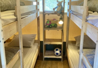 Binnenin een safaritent bij Recreatiepark Keiheuvel, België, met stapelbedden en kinderspeelgoed op rekken.