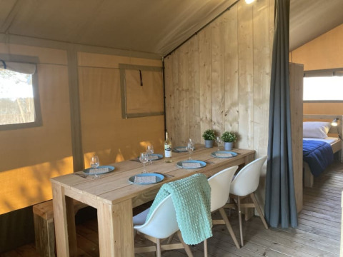 Interieur van een safaritent met eetgedeelte en slaapkamer bij Recreation Park Keiheuvel, België.