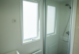 Bathroom with shower cabin and window at Sun Lodge, Camping Les Bouleaux in France, bright interior.
