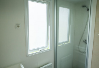 Bagno con cabina doccia e finestra al Sun Lodge, Camping Les Bouleaux in Francia, interni chiari.