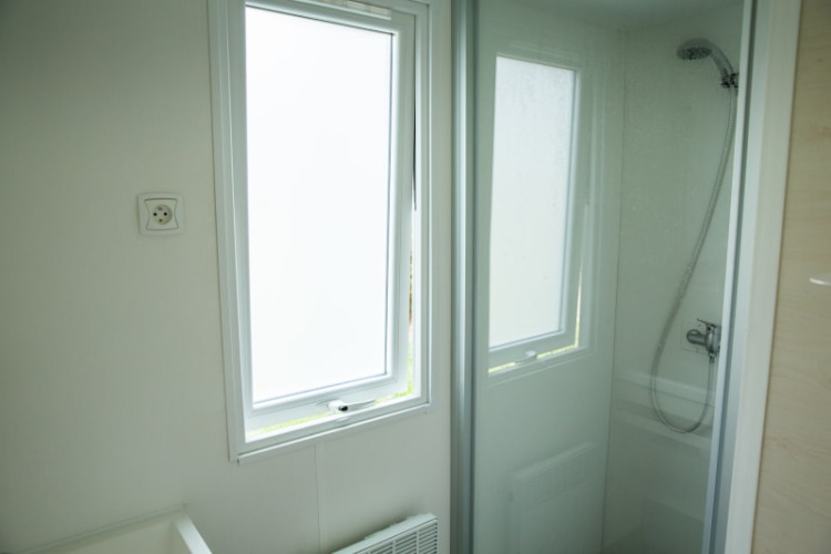 Bathroom with shower cabin and window at Sun Lodge, Camping Les Bouleaux in France, bright interior.