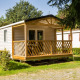 Solrig Sun Lodge, et moderne mobilhome med træveranda, placeret i naturskønne grønne omgivelser.