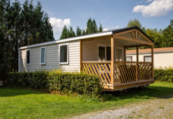 Vista exterior de la Sun Lodge en Camping Les Bouleaux, Francia, con porche de madera y jardín verde.